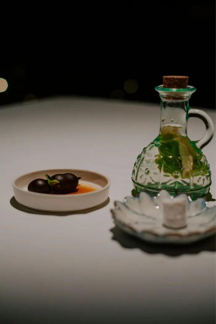 Jaggery-stewed tamarind beside a glass carafe of herbs