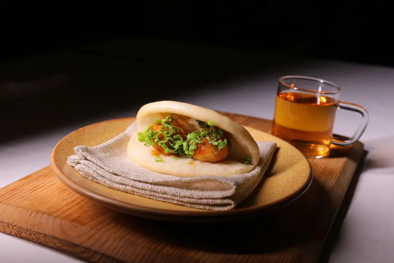 Clear soup served with a bao on a wooden board